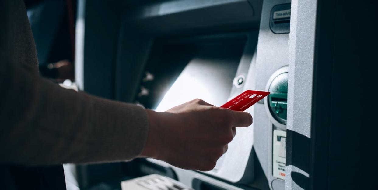 close up of young woman inserting her bank card into automatic cash machine in the city withdrawing money, paying bills, checking account balances, transferring money privacy protection, internet and mobile security concept