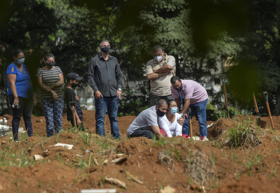 Relatives grieve as they attend a burial service of a person who died from complications related to COVID-19 at the Vila Formosa cemetery in Sao Paulo, Brazil, Thursday, March 11, 2021. One year after the World Health Organization officially declared the spread of the coronavirus a pandemic, Brazil is reporting almost 2,000 deaths per day. (AP Photo/Andre Penner)