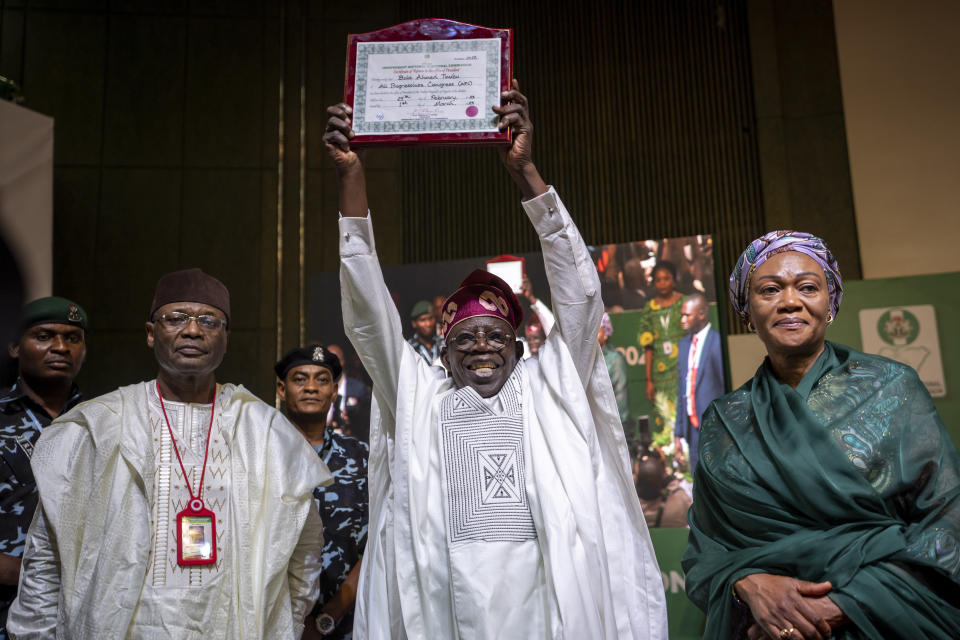 FILE- President-Elect Bola Tinubu, center, displays his certificate, accompanied by his wife Oluremi Tinubu, right, and chairman of the Independent National Electoral Commission (INEC) Mahmood Yakubu, left, at a ceremony in Abuja, Nigeria Wednesday, March 1, 2023. Nigeria's Bola Tinubu will take over the reins in Africa's most populous country at a period of unprecedented challenges, leaving some citizens hopeful for a better life and others sceptical that his government would perform better than the outgoing one on Monday May 29, 2023. (AP Photo/Ben Curtis, File)