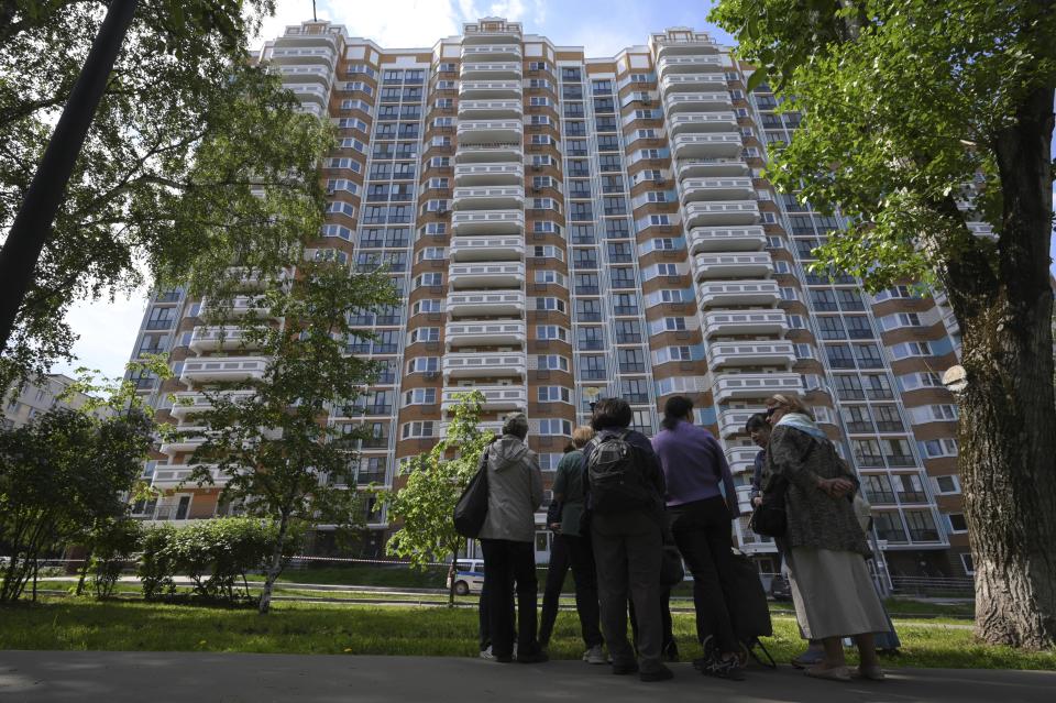 Moskau: Menschen blicken auf ein Wohnhaus, das Berichten zufolge durch eine ukrainische Drohne beschädigt wurde. (Bild: Uncredited/AP/dpa )