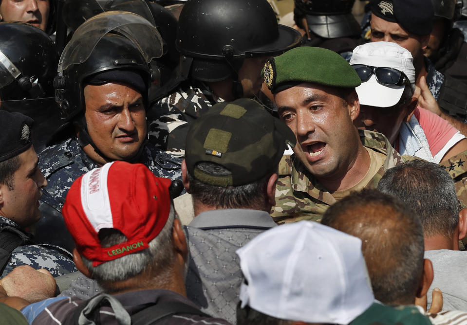 Lebanese army officer, center, shouts as trying to clams down his retired comrades, who are protesting and trying to enter the parliament building where lawmakers and ministers are discussing the draft 2019 state budget, in Beirut, Lebanon, Friday, July 19, 2019. The budget is aimed at averting a financial crisis in heavily indebted Lebanon. But it was met with criticism for failing to address structural problems. Instead, the budget mostly cuts public spending and raises taxes. (AP Photo/Hussein Malla)