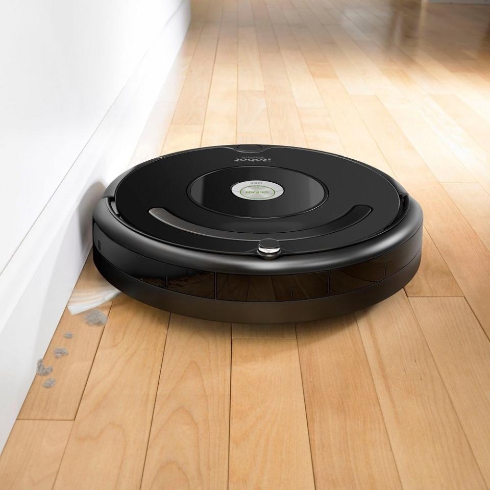 Robotic vacuum cleaner operating on a wooden floor, picking up debris