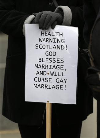 A woman holds a placard outside the Scottish Parliament in Edinburgh, Scotland February 4, 2014. REUTERS/Russell Cheyne