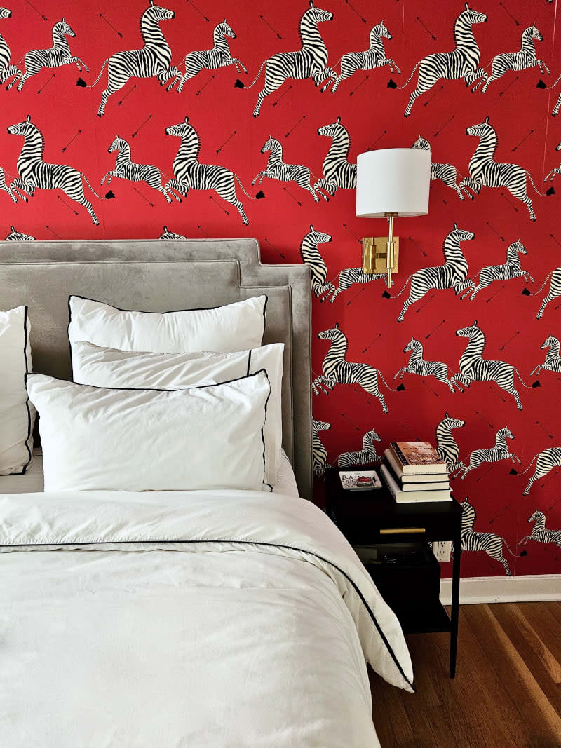 bedroom with red zebra wallpaper accent wall and bed with gray sueded headboard