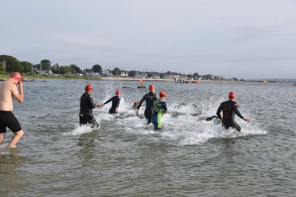 Triathlon athletes make their way into the water near Fort Taber in New Bedford's South End during the 2023 Whaling City Tri & Du on July 16. Public safety personnel assisted lifeguards and athletes in the water that day as high winds made for a strong current.