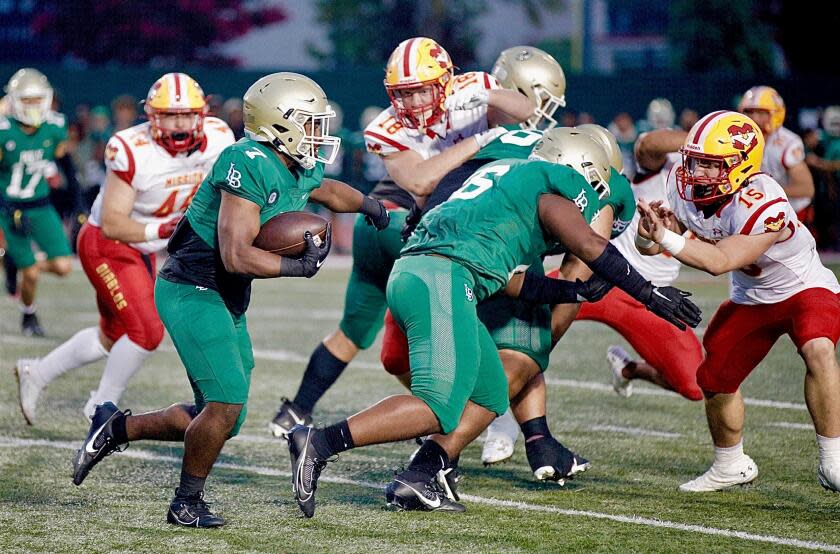 Long Beach Poly running back Joshua Cason follows his blockers for a 20-yard gain against Mission Viejo.