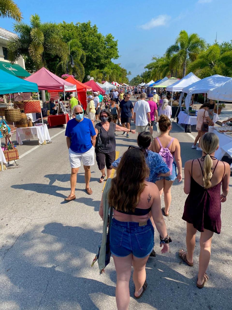 People walk the Third Street South Farmers Market in Naples, Florida, on April 17, 2021.