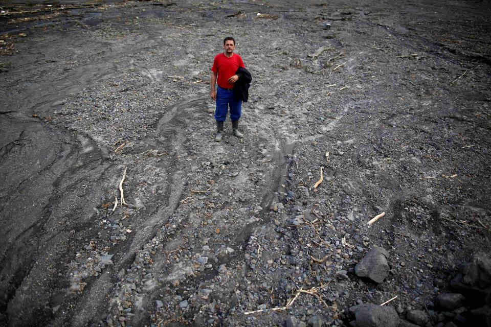 Zehid Kovacevic poses in his flood-damaged field, which he used to grow potatoes, in Topcic Polje