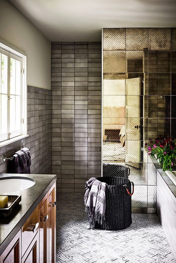 <p>A great way to add more privacy to a shared bathroom? Separate the toilet area from the tub and sink zones with a partition. Romanek Design Studio even manages to make it look sexy with smokey mirrored tiles that also make it feel larger and exude an airy of mystery and intrigue. They silver zellige tiles enhance this mood even more.</p>