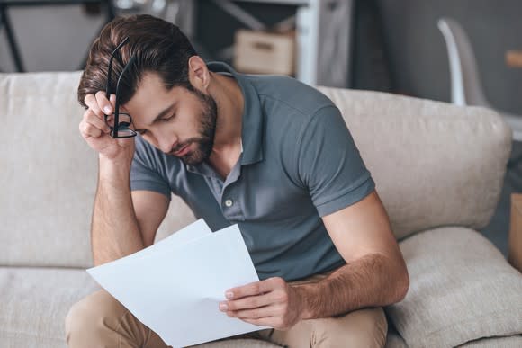 Man holding head while reading a document.