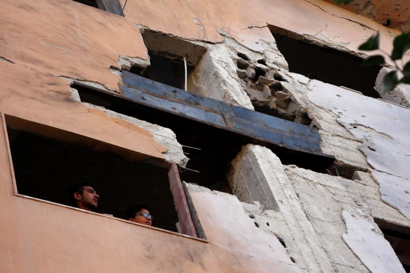 Boys look out the window of a building, damaged from an Israeli attack in Damascus