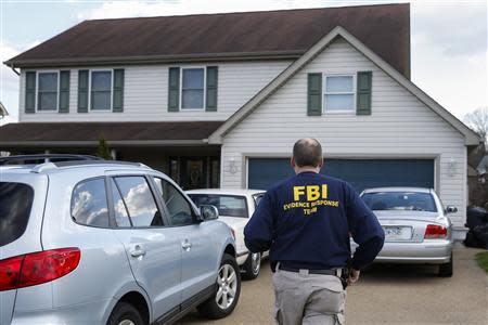 An FBI agent enters the family home of a suspect after a series of knife attacks at at Franklin Regional High School in Murrysville, Pennsylvania April 9, 2014. REUTERS/Shannon Stapleton