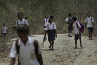 In this Oct. 22, 2018, file photo, students walk on dirt road after school in O'of village in West Timor, Indonesia. Children in this impoverished region of Indonesia often must walk long distances to school. Upon graduation, their job opportunities are limited, leaving them with few options beyond a lifetime of subsistence farming in a land punished by drought. (AP Photo/Tatan Syuflana, File)