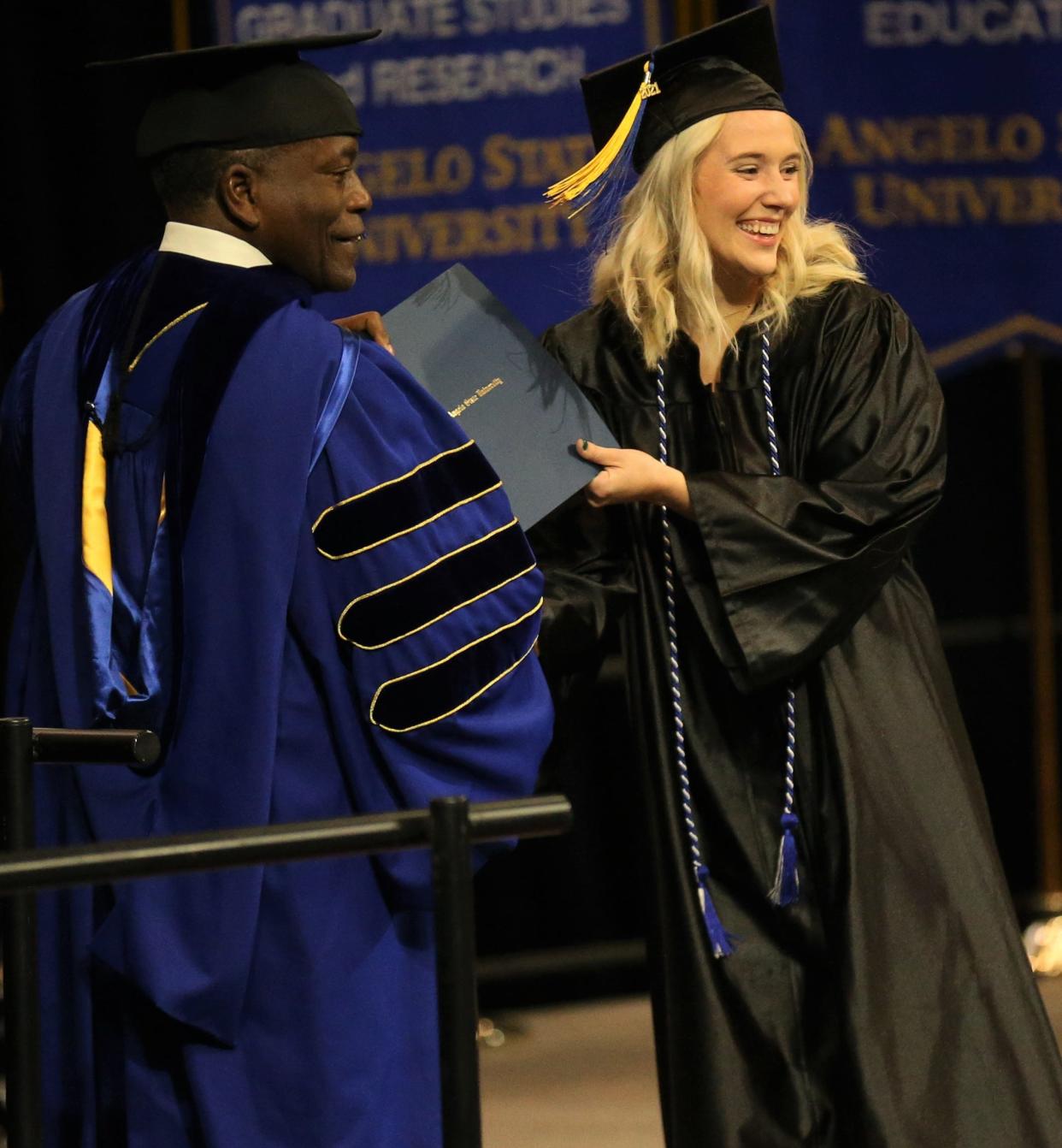 Angelo State University President Ronnie Hawkins hands a diploma to a graduate during fall commencement ceremonies at the Junell Center on Dec. 11, 2021.