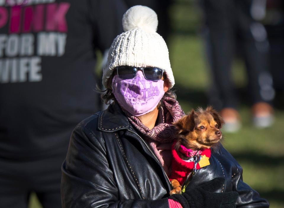 A woman keeps herself and dog warm during ceremonies at the start of the Susan G. Komen 2022 West Palm Beach MORE THAN PINK Walk Saturday, January 29, 2022. The organization describes the event as a time to share stories, laughter, and tears, as well as to raise money that saves lives, while celebrating survivors, those living with breast cancer, and lost loved ones.