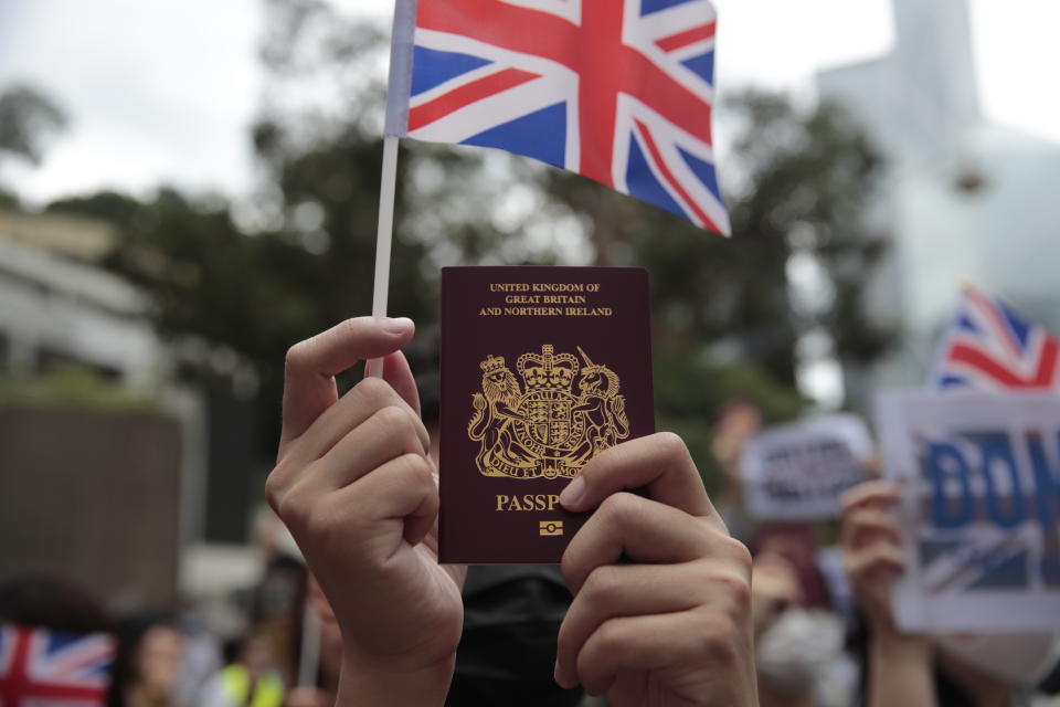 A protestor holds up his British passport and participates in a peaceful demonstration outside the British Consulate in Hong Kong, Sunday, Sept. 1, 2019. The operator of the express train to Hong Kong's airport has suspended service as pro-democracy protesters gathered there following a day of violent clashes with police. Protesters gathered at the airport after online calls to disrupt travel. (AP Photo/Jae C. Hong)