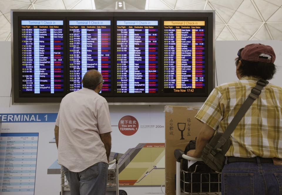 Passengers look at an information board which shows nearly all departure flights were cancelled, in anticipation of typhoon Usagi, at Hong Kong Airport September 22, 2013. (REUTERS/Bobby Yip)