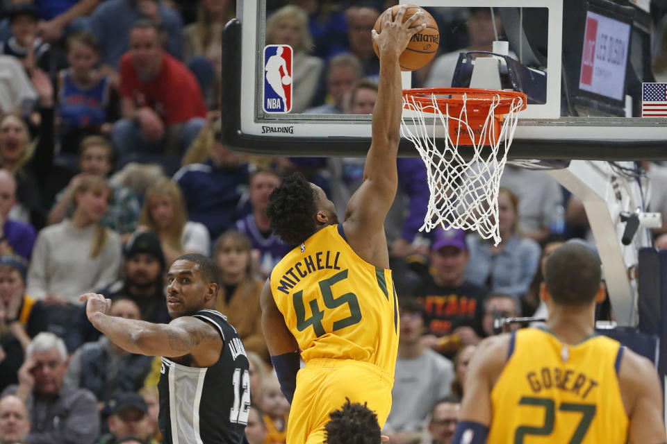 Utah Jazz guard Donovan Mitchell (45) dunks next to San Antonio Spurs forward LaMarcus Aldridge (12) during the first half of an NBA basketball game Friday, Feb. 21, 2020, in Salt Lake City. (AP Photo/Rick Bowmer)