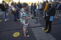 A woman wearing a garment with a TV test card pattern shows her electronic ticket to to hostess as she queues for admission to the first semifinal of the Eurovision Song Contest at Ahoy arena in Rotterdam, Netherlands, Tuesday, May 18, 2021.The competition featuring 39 national songs from nations across Europe as well as Australia and Israel is one of the largest events staged in Europe since the global pandemic began and comes as the continent begins to tentatively ease coronavirus lockdown measures. A crowd of 3,500, tested ahead of time, will be allowed into the Ahoy arena. The number represents a fraction of its capacity to watch the performances live. (AP Photo/Peter Dejong)