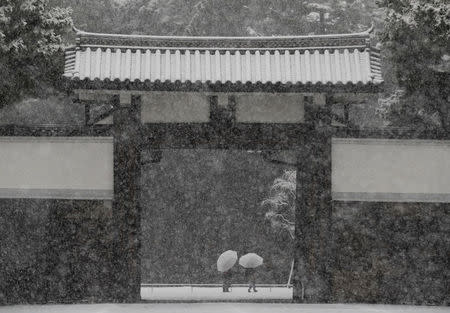 People holding umbrellas make their way in the heavy snow at the Imperial Palace in Tokyo, Japan January 22, 2018. REUTERS/Kim Kyung-Hoon