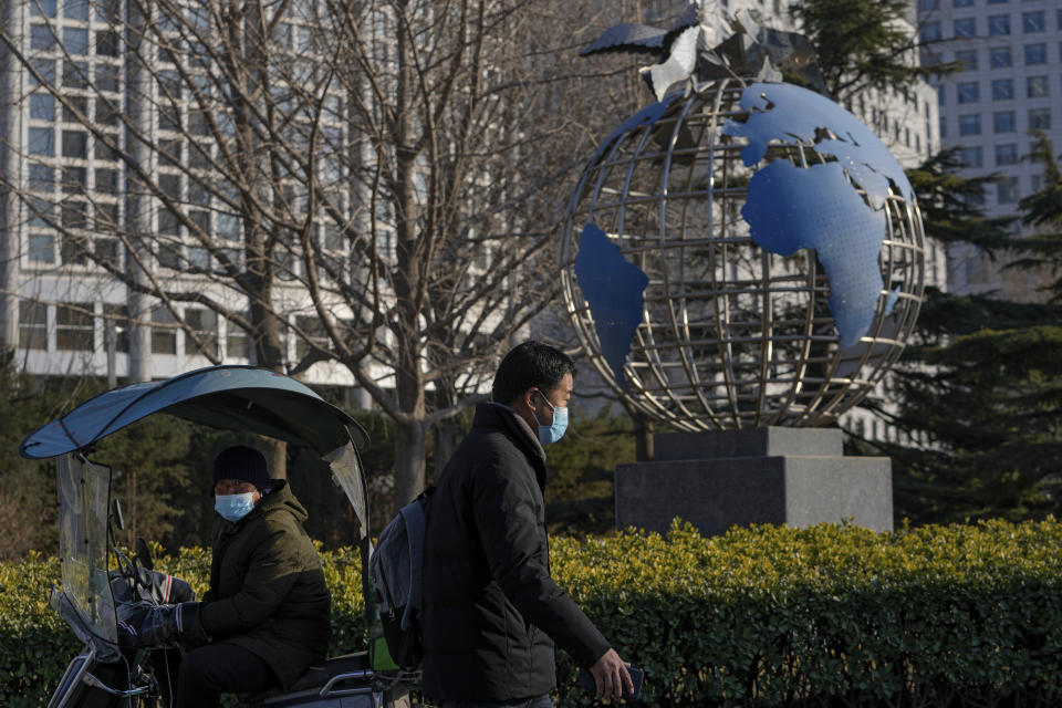 A man walks by a motorist near a globe sculpture displayed outside the Ministry of Foreign Affairs office in Beijing, Thursday, Feb. 24, 2022. China repeated calls for talks to resolve the crisis in Ukraine on Thursday while refusing to criticize Russia's attack and accusing the U.S. and its allies of worsening the situation. (AP Photo/Andy Wong)