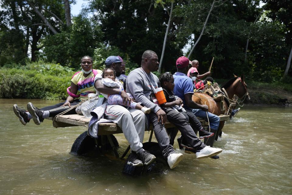 Migrants cross the Acandi River on a horse cart in Acandi, Colombia, Tuesday, Sept. 14, 2021. The migrants, following a well-beaten, multi-nation journey towards the U.S., will continue their journey through the jungle known as the Darien Gap. (AP Photo/Fernando Vergara)