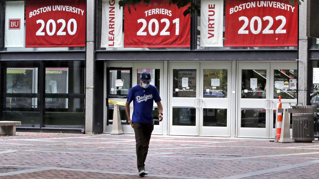 FILE - Weston Koenn, a graduate student from Los Angeles, leaves the Boston University student union building as he walks through the student-less campus in Boston, July 23, 2020. Most of the COVID-19 booster mandates so far have been at small liberal arts colleges in the Northeast, but the list includes some as big as Boston University and as far away as the University of Notre Dame in Indiana and the University of New Mexico. (AP Photo/Charles Krupa, File)