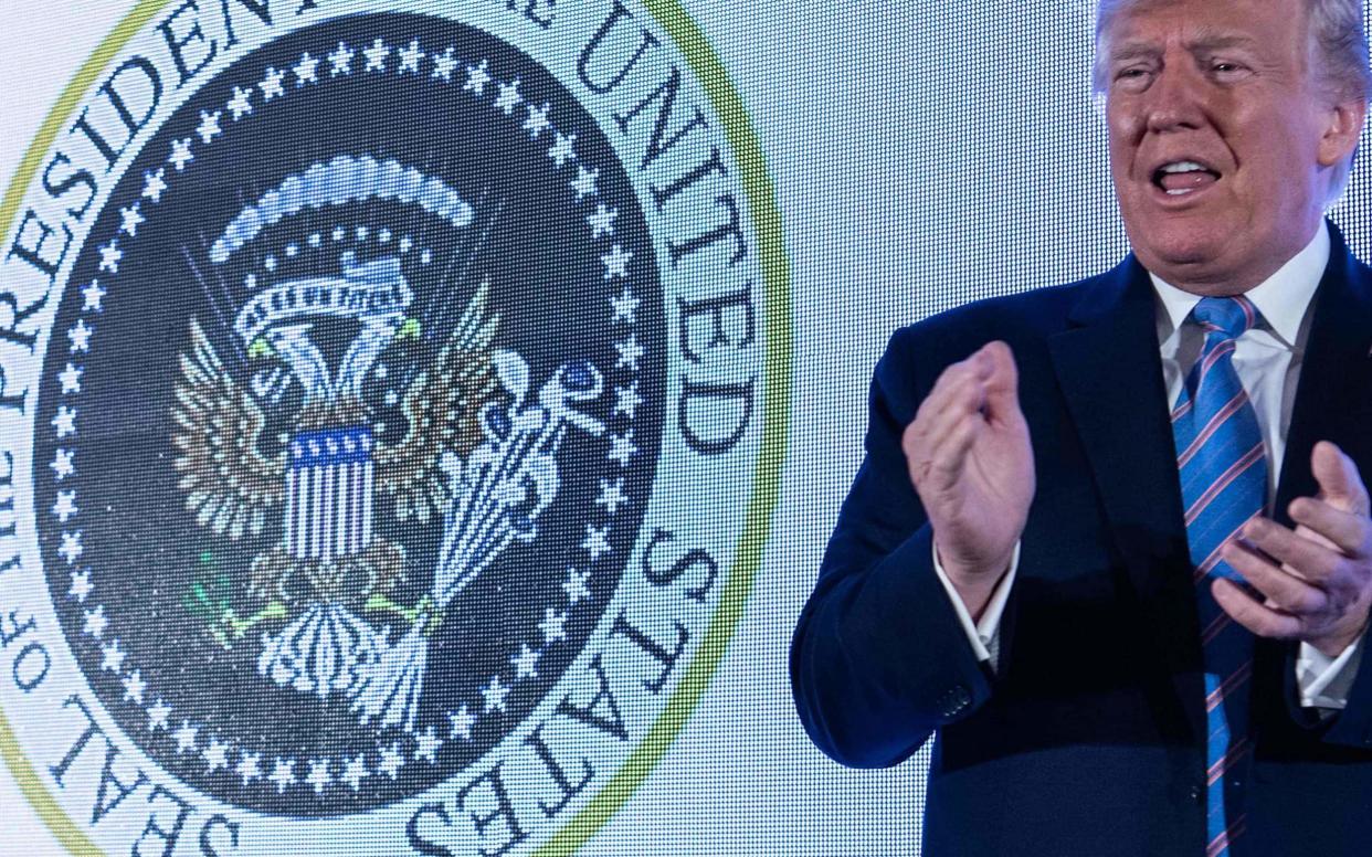 Donald Trump alongside the fake seal, which features an eagle holding golf clubs, on Tuesday - AFP