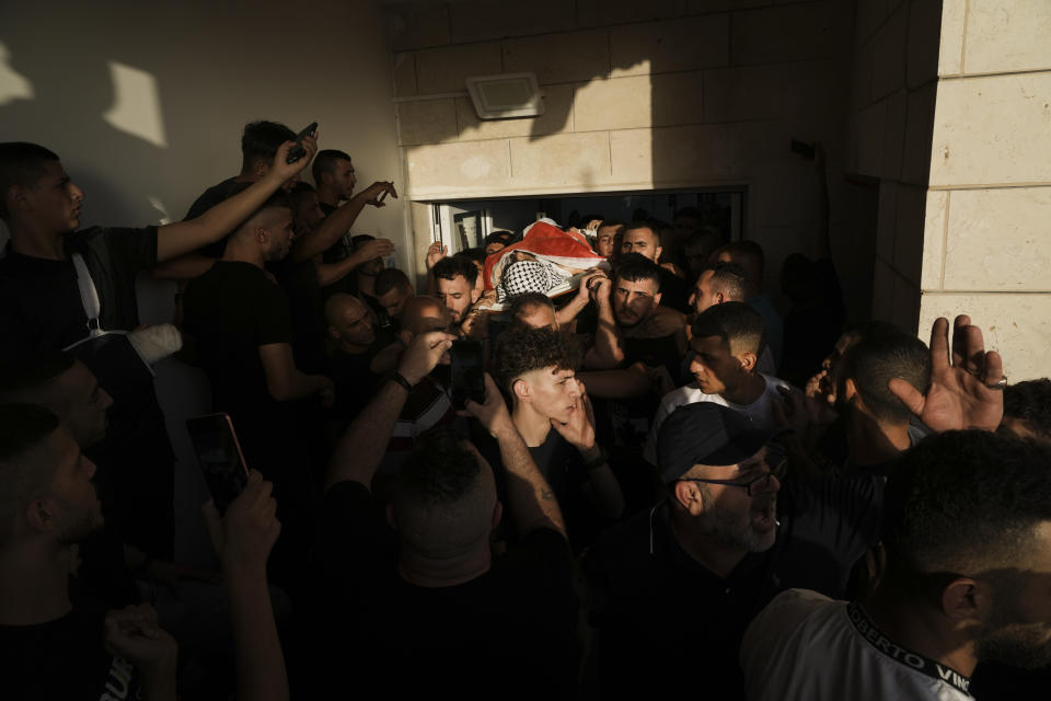 Palestinian mourners carry the body of Fayez Damdoum in the West Bank village of Azariyah, Saturday, Oct. 1, 2022. Israel's paramilitary border police said forces shot a protester who attempted to throw a firebomb at them as they came to disperse a demonstration. It said demonstrators threw stones and explosives at them. The Palestinian Health Ministry identified the dead youth as 18-year-old Fayez Damdoum. (AP Photo/Mahmoud Illean)