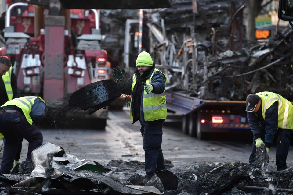 Workers clean up the debris of a burnt train and vehicles in Dublin (Getty Images)