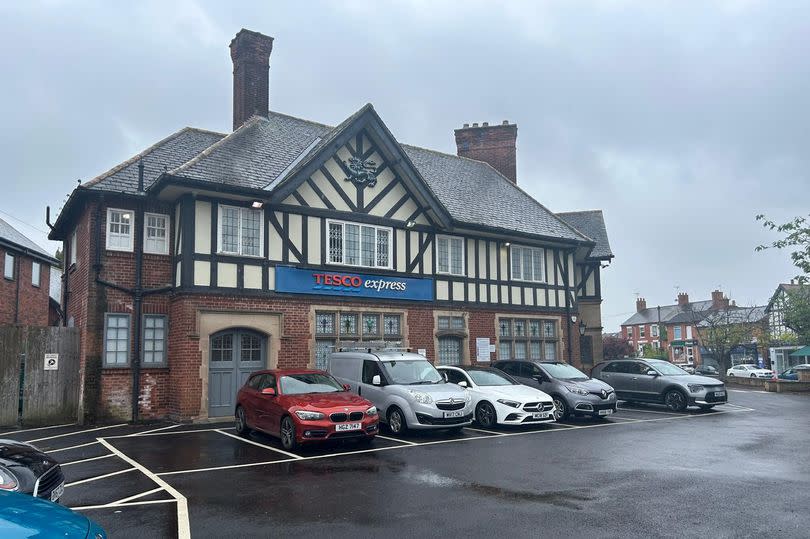 General exterior view on wet and grey day of Tesco Express in old Georgian-style former pub building in Radcliffe-on-Trent with five cars parked in front