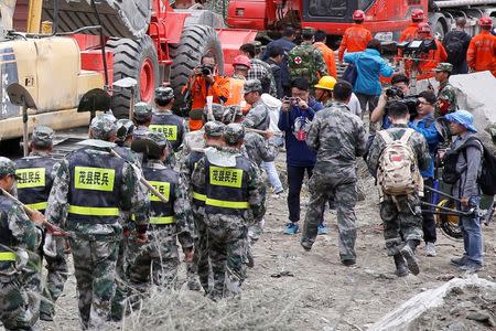 Members of the media take pictures of rescue workers at the site of a landslide in the village of Xinmo, Mao County, Sichuan Province, China June 26, 2017. REUTERS/Aly Song