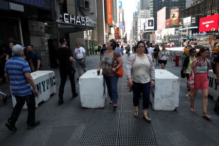 People walk between newly erected concrete barricades outside the 3 Times Square building in Times Square where a speeding vehicle struck pedestrians Thursday in New York City, U.S., May 19, 2017. REUTERS/Mike Segar