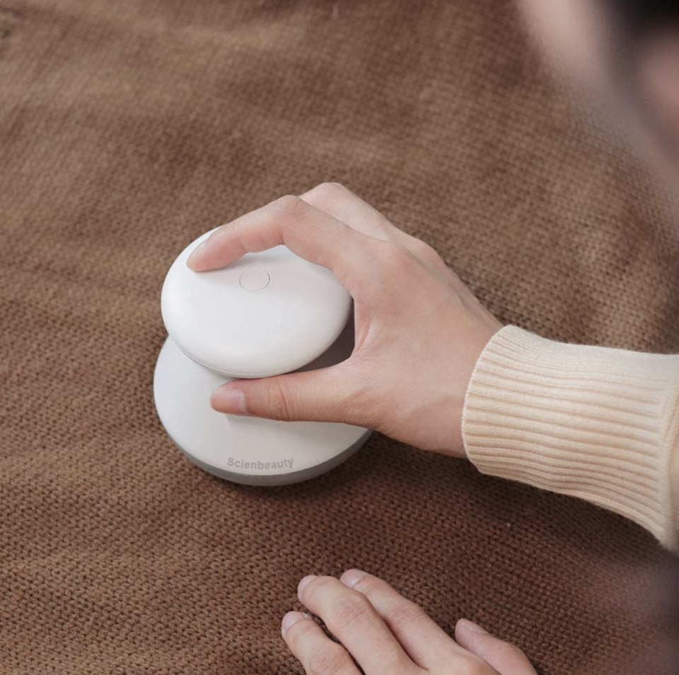 woman using Scienbeauty Fabric Shaver  on brown sweater (Photo via Amazon)