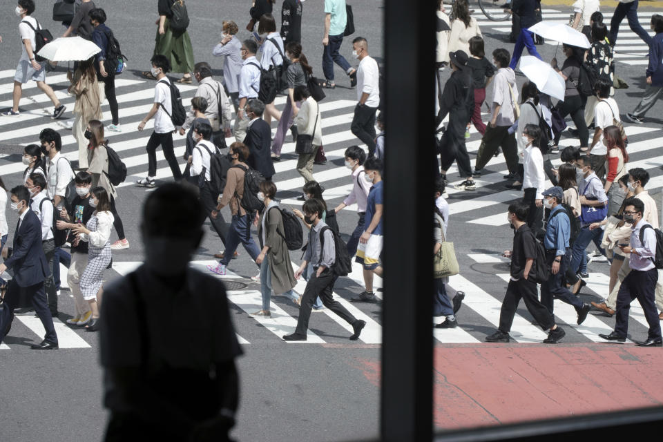 A man sits near a window as people wearing face masks walk along a pedestrian crossing at Shibuya district Thursday, Sept. 30, 2021, in Tokyo. Japan will lift its COVID-19 state of emergency in all of the regions at the end of September. Fumio Kishida, the man soon to become Japan’s next prime minister, says he believes raising incomes is the only way to get the world’s third-largest economy growing again. Top of Kishida’s to-do list is another big dose of government spending to help Japan recover from the COVID-19 shock. (AP Photo/Eugene Hoshiko)