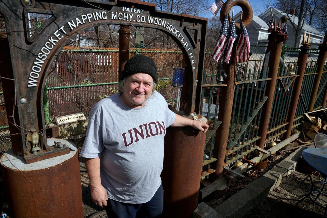 Russell Archambault, a landlord in Woonsocket, stands at the entrance to the outdoor courtyard he built for his rooming house residents.