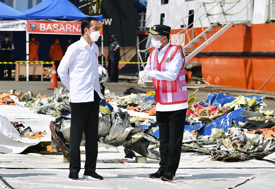 In this photo released by the Indonesian Presidential Palace, President Joko Widodo, left, confers with Transportation Minister Budi Karya Sumadi as they inspect pieces of the Sriwijaya Air flight SJ-182 retrieved from the Java Sea where the passenger jet crashed on Jan. 9, at Tanjung Priok Port in Jakarta, Indonesia, Wednesday, Jan. 20, 2021. The Indonesian leader on Wednesday reassured relatives of the passengers killed when the plane nosedived into the Java Sea that compensation is paid to family members struggled with grief. (Laily Rachev, Indonesian President Palace via AP)