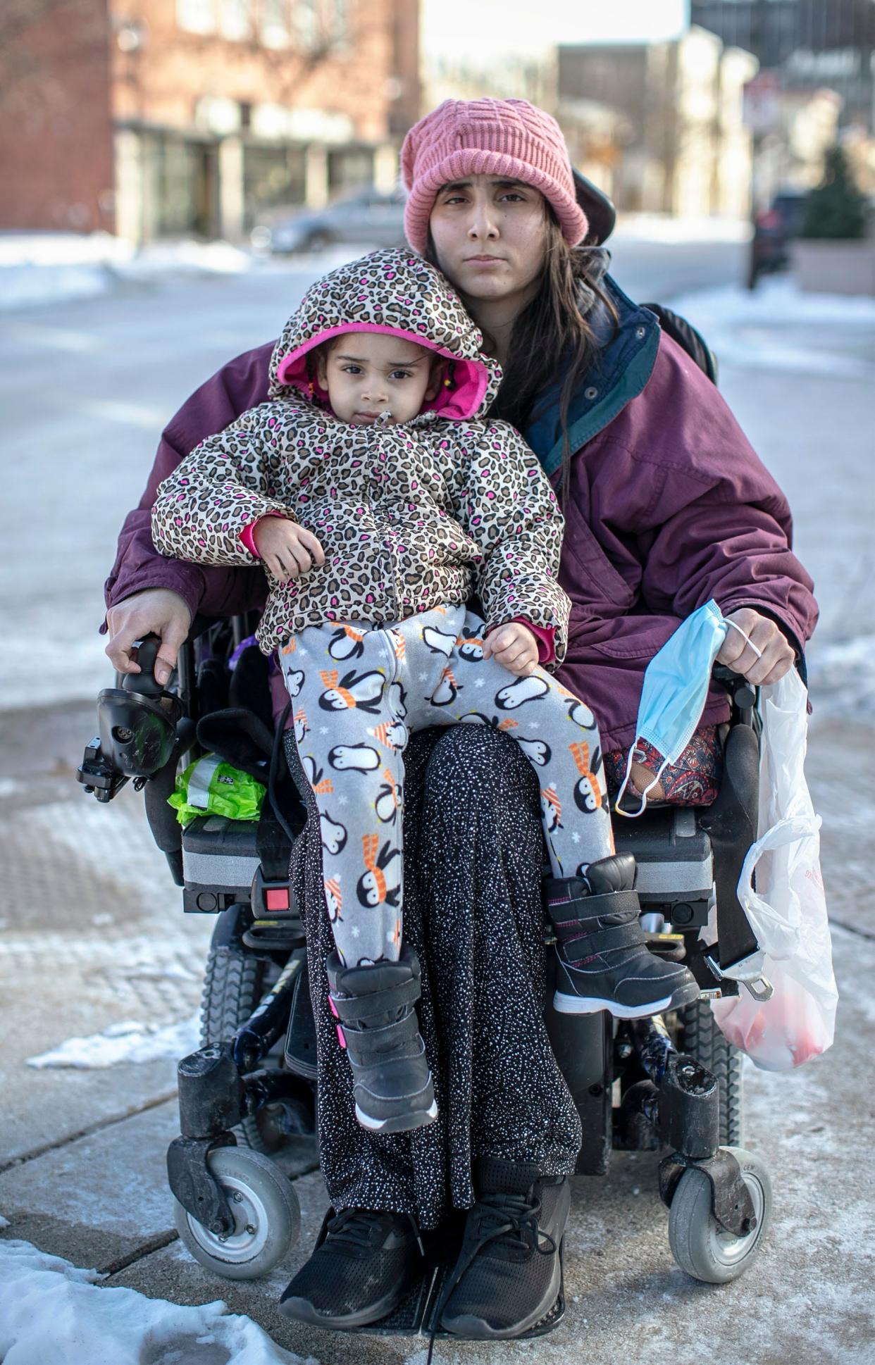 Ashley Lagoo-Mckinnie and her daughter, Lyanna Brown-Lagoo, sit on the corner near the Above and Beyond Children's Museum, Jan. 28, 2022, in Sheboygan. Ashley, who uses a wheelchair, and her young daughter live in a shelter in Sheboygan.