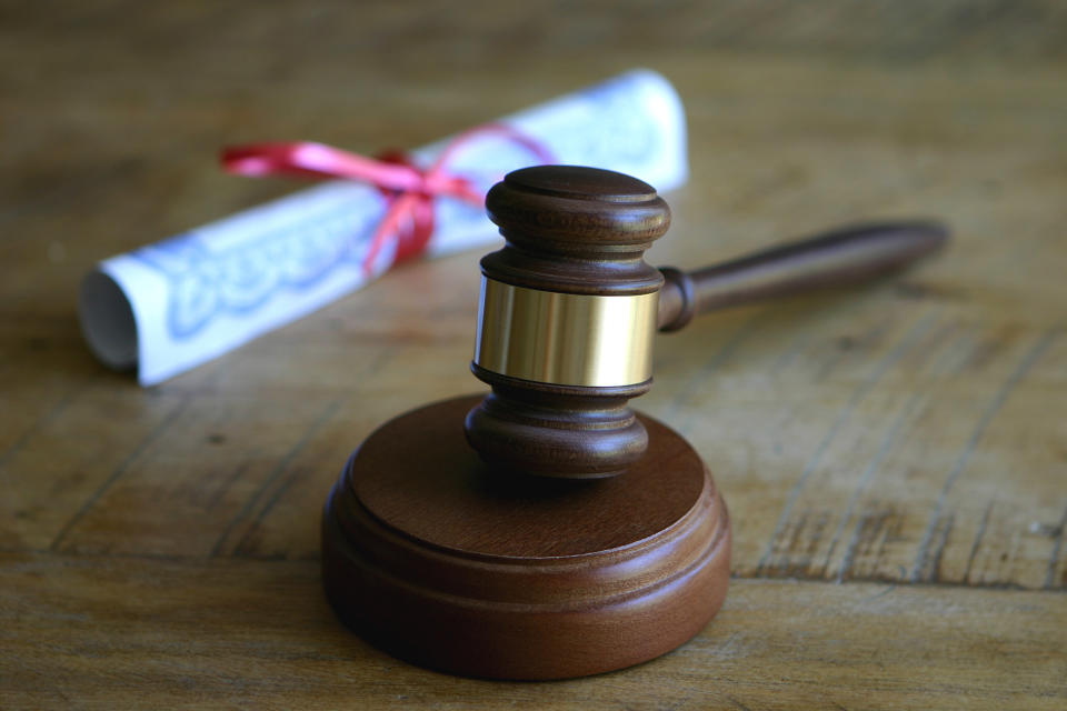 A diploma and gavel sit on a wooden surface