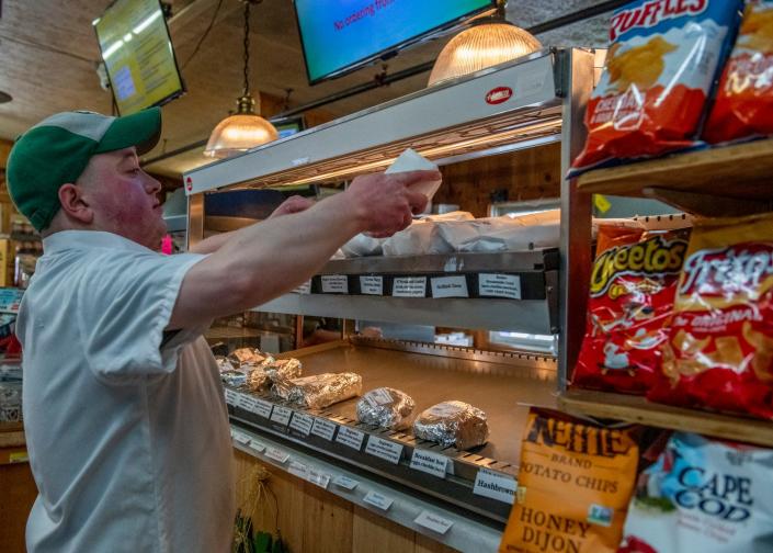 Jeremy Pagano, 27, stocks food at H.B. Provisions, a beloved general store for sale in Kennebunkport, March 9, 2022.  The store is listed for sale at $3.8 million.