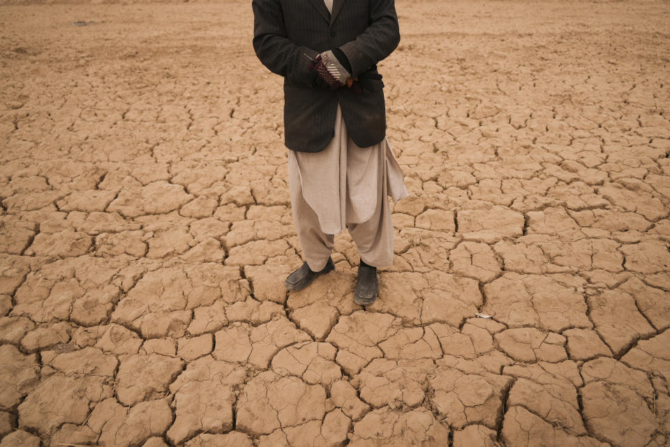 Abdul Haqim surveys his barren field where he used to grow wheat to feed his family of 18 people, in Hachka, Afghanistan, Monday, Dec. 13, 2021. Severe drought has dramatically worsened the already desperate situation in Afghanistan forcing thousands of people to flee their homes and live in extreme poverty. Experts predict climate change is making such events even more severe and frequent. (AP Photo/Mstyslav Chernov)