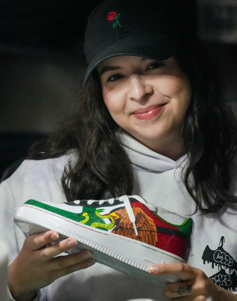 Mikayla Enriquez, 25, of Milwaukee holds up a shoe she hand-painted. She runs a business called Moe Kickz from her East Side apartment.