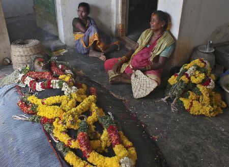 Chanaga Ratnam (R) sits next to the body of her husband Chanaga Aankaiah at their residence near Guduru town in Nellor district in Andhra Pradesh, May 29, 2015. REUTERS/Stringer