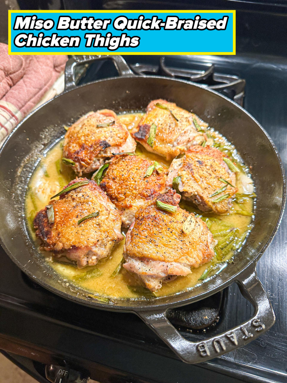 Four seasoned pork chops cooking in a skillet on a stove