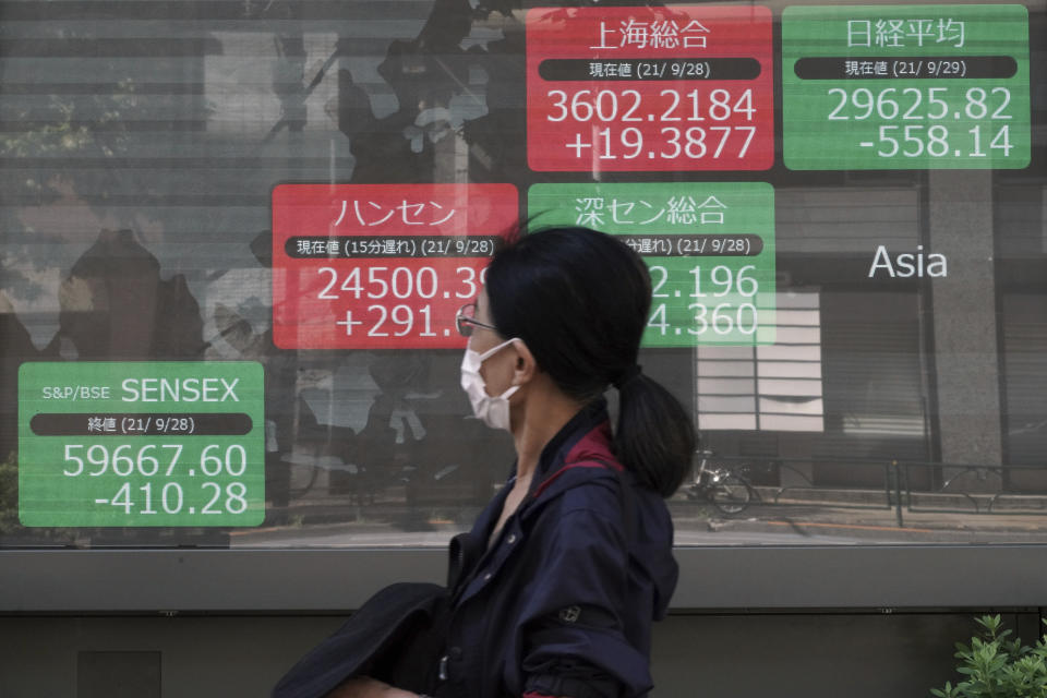 A woman wearing a protective mask walks in front of an electronic stock board showing Japan's Nikkei 225 and other Asian indexes at a securities firm Wednesday, Sept. 29, 2021, in Tokyo. Asian shares fell sharply on Wednesday after a broad slide on Wall Street as investors reacted to a surge in U.S. government bond yields. (AP Photo/Eugene Hoshiko)