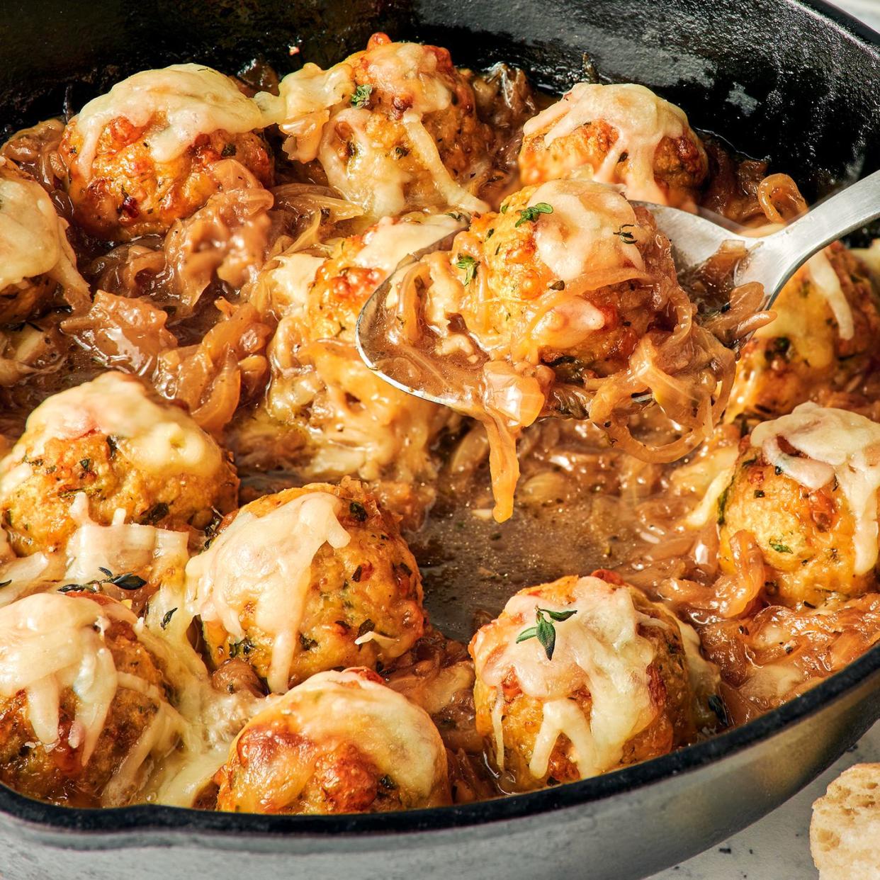 chicken meatballs in a skillet with onions and melty cheese