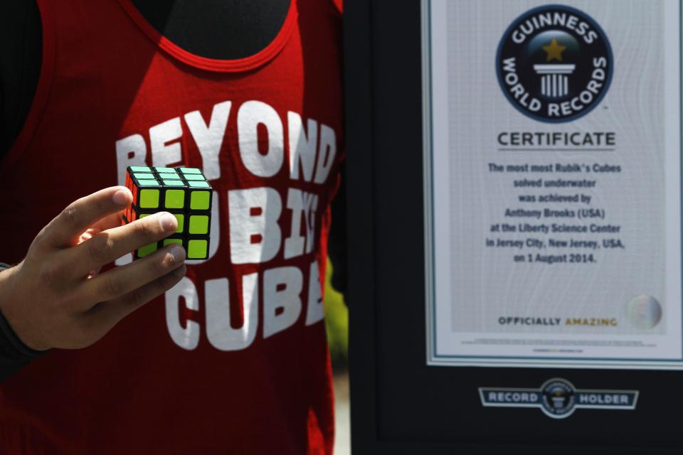 North American Speed Cube Champion Anthony Brooks poses with the Guinness World Records title for "Most Cubes Solved Underwater In One Breath", at the National Rubik's Cube Championship at Liberty Science Center in Jersey City