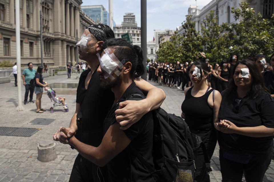 Anti-government demonstrators, wearing eye patches, perform in front of the Supreme Court in Santiago, Chile, Monday, Nov. 18, 2019. According to the Medical College of Chile at least 230 people have lost sight after being shot in an eye in the last month while participating in the demonstrations over inequality and better social services. (AP Photo/Esteban Felix)