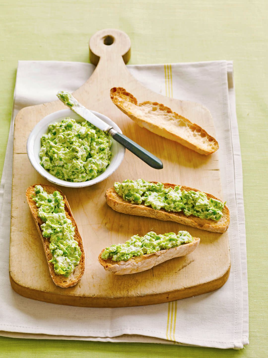 ricotta pea spread on sliced bread on a wooden serving baord