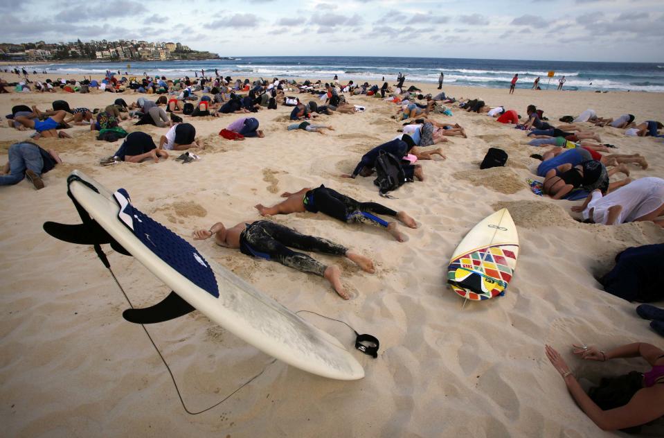 A group of around 400 demonstrators participate in a protest by burying their heads in the sand at Sydney's Bondi Beach November 13, 2014. Hundreds of protesters participated in the event, held ahead of Saturday's G20 summit in Brisbane, which was being promoted as a message to Australian Prime Minister Tony Abbott�s government that, "You have your head in the sand on climate change". REUTERS/David Gray (AUSTRALIA - Tags: POLITICS CIVIL UNREST SOCIETY ENVIRONMENT)